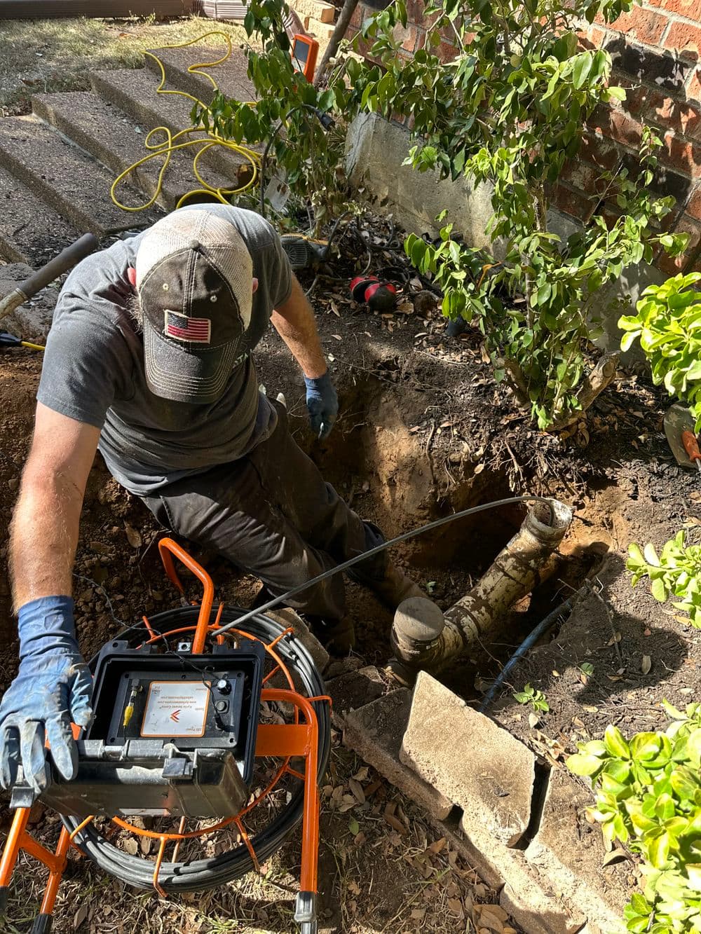 Technician using equipment to inspect underground plumbing in a residential yard.
