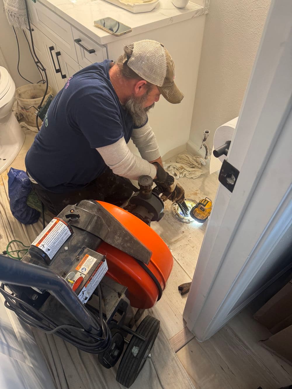 Plumber repairing bathroom drain with tools and equipment in a modern setting.